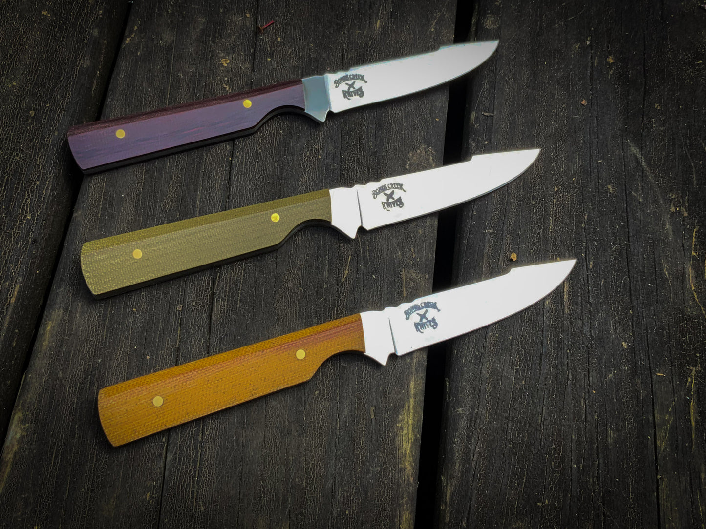 Bonds Creek Knives Fin & Feather, showing three color options on the handle, burgundy, green, and yellow 