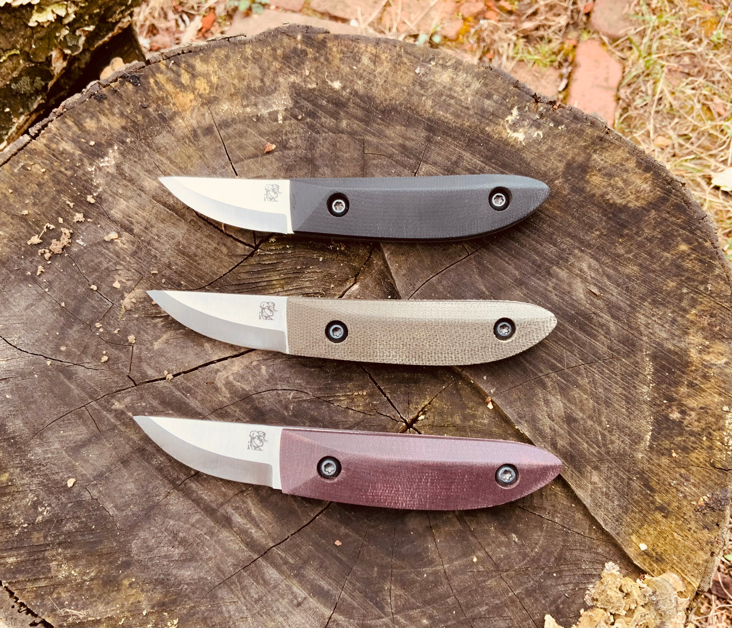 Kerf Carver Knife shown in black, green, and double red micarta