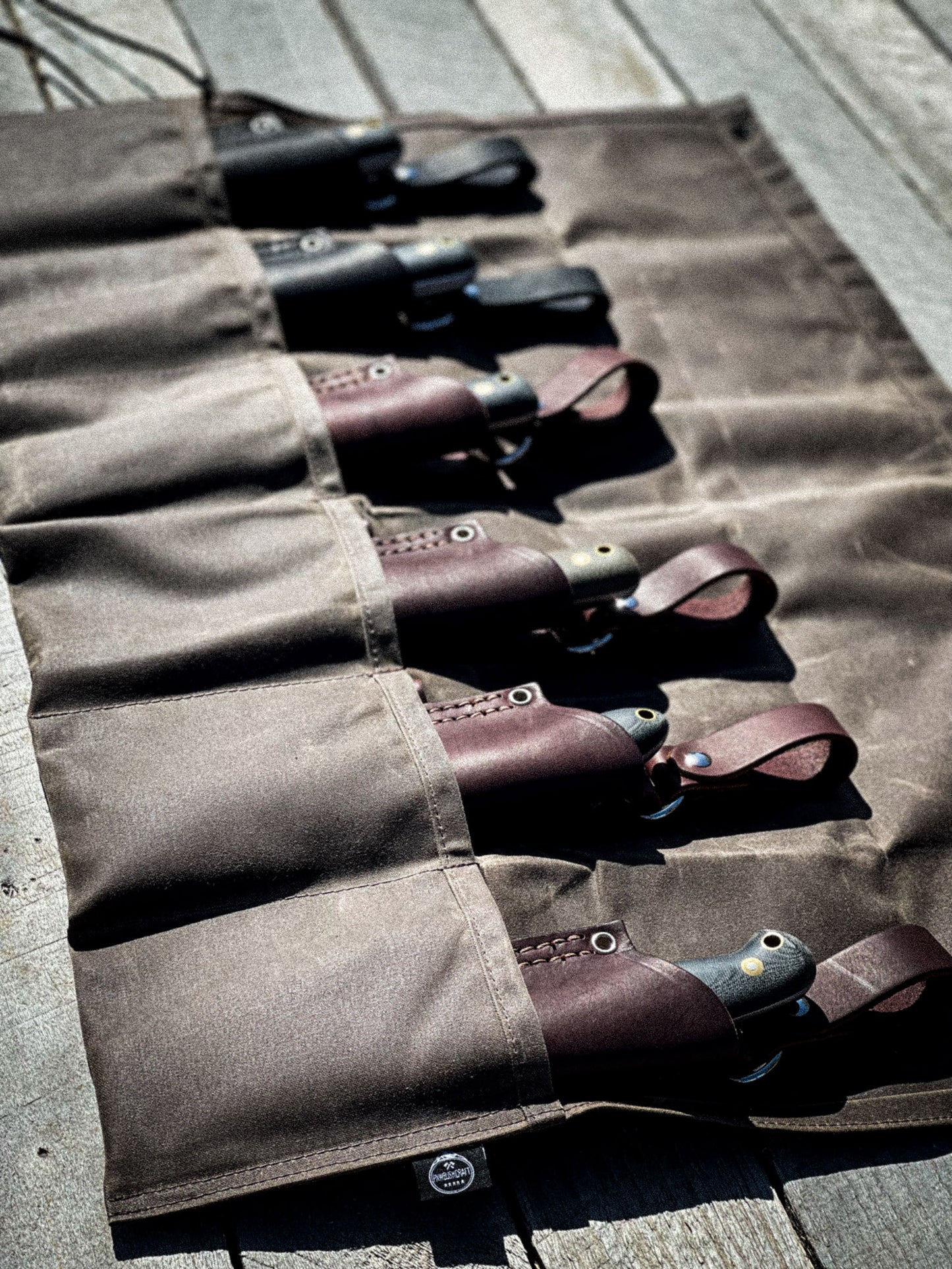 Alder Waxed Canvas 6 Pocket Tool Roll in dark brown holding knives